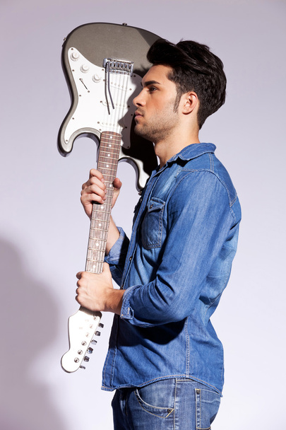Young guitarist holding an electric guitar - Valokuva, kuva