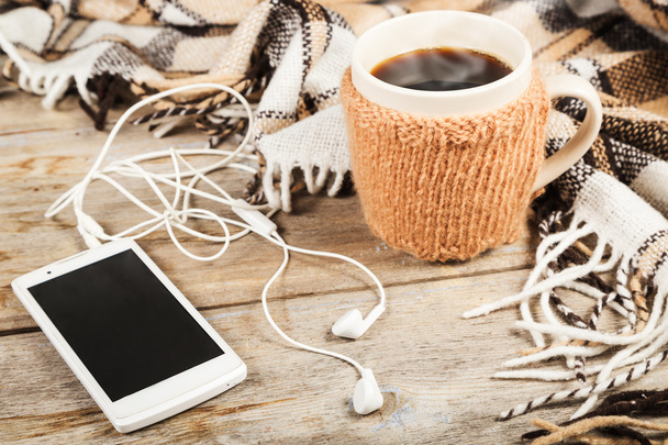 Hot coffee in a large cup, mobile phone with headphones - 写真・画像
