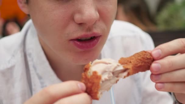 ο τύπος τρώει τηγανητό κοτόπουλο σε ένα closeup εστιατόριο γρήγορου φαγητού - Πλάνα, βίντεο
