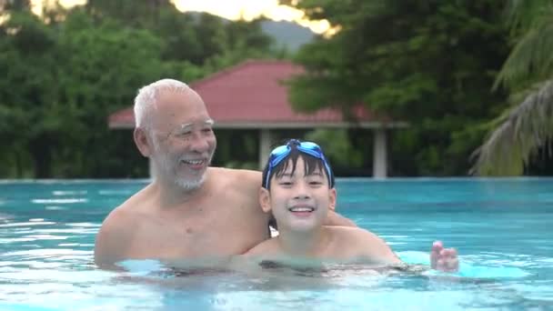 Onnellinen aasialainen perhe pelaa uima-altaassa, Aasian lastenlapset ja isovanhemmat uima-altaassa
. - Materiaali, video