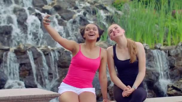 Nuoria naisia ottamassa selfietä vesiputouksen lähellä. Seflietä käyttävät monirotuiset naiset
 - Materiaali, video