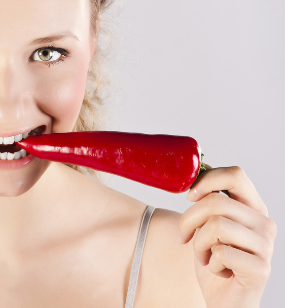 Beautiful woman teeth eating red hot chili pepper - Fotó, kép