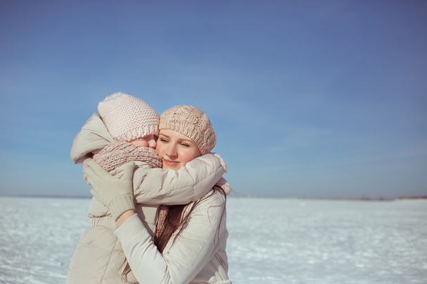 Portrait of little daughter hugs his mother in winter - Photo, Image