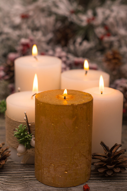 Fir branch in snow, lighted candle, cone on wooden background. Christmas theme - Photo, image