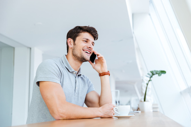 Cheerful man talking on cell phone while having coffee break - Photo, Image