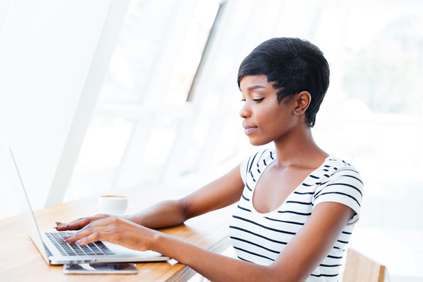 Portrait of a casual smiling african businesswoman using laptop computer - Zdjęcie, obraz