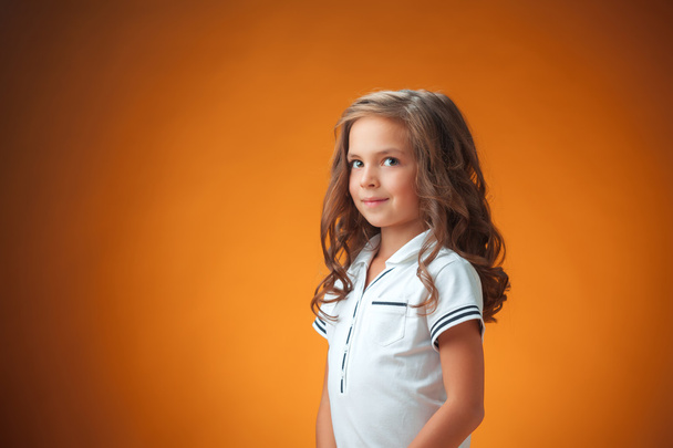 The cute cheerful little girl on orange background - Фото, изображение