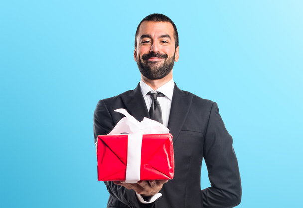 Businessman holding a gift - Foto, afbeelding
