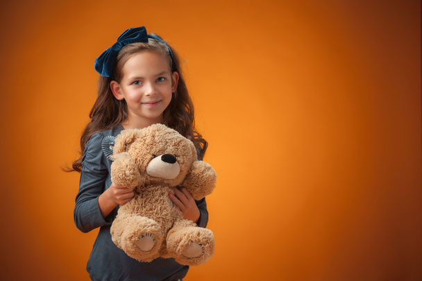 The cute cheerful little girl on orange background - Zdjęcie, obraz