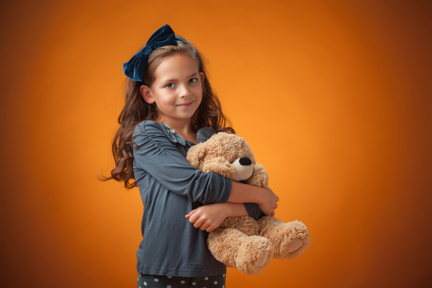 The cute cheerful little girl on orange background - Valokuva, kuva