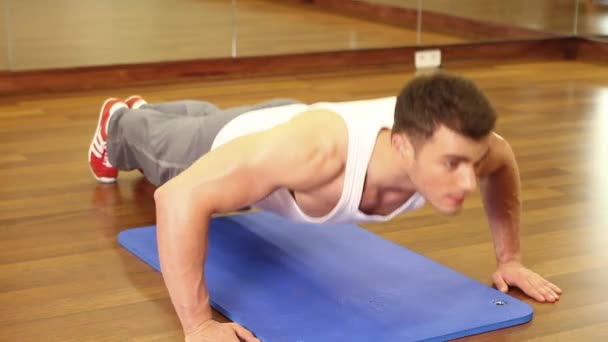 Handsome sporty man is exercising in gym centre - Footage, Video