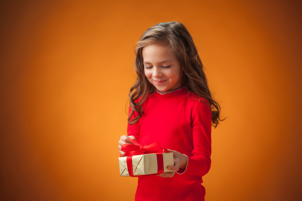 The cute cheerful little girl on orange background - Photo, Image