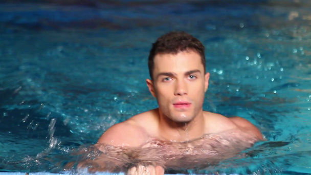 przystojny facet jest pływanie na stronie basenu - Materiał filmowy, wideo