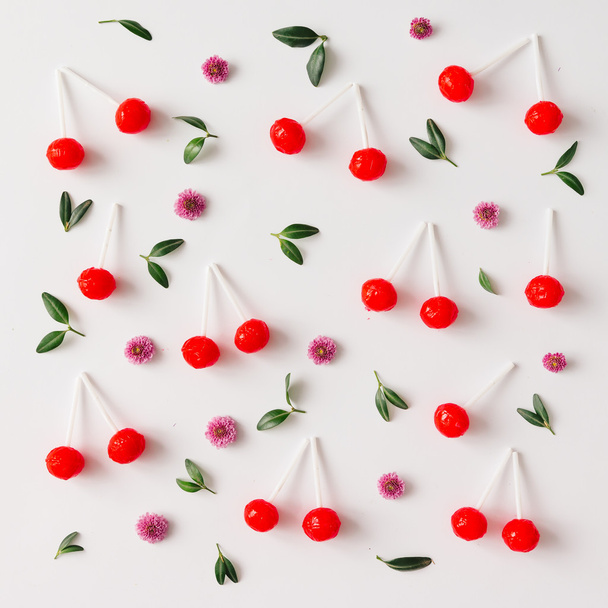 Pattern made of red cherry lollipops, leaves, and flowe - Fotografie, Obrázek