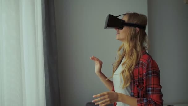 Mulher no fone de ouvido VR olhando para os objetos em realidade virtual. VR é uma tecnologia de computador que simula uma presença física e permite ao usuário interagir com o ambiente
. - Filmagem, Vídeo
