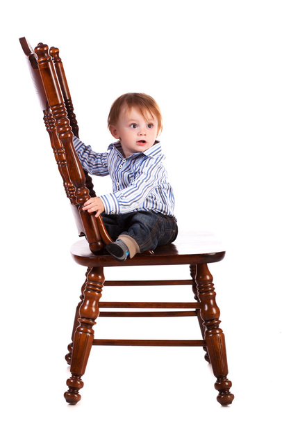 Baby on a big wooden chair in a studio. isolated - 写真・画像