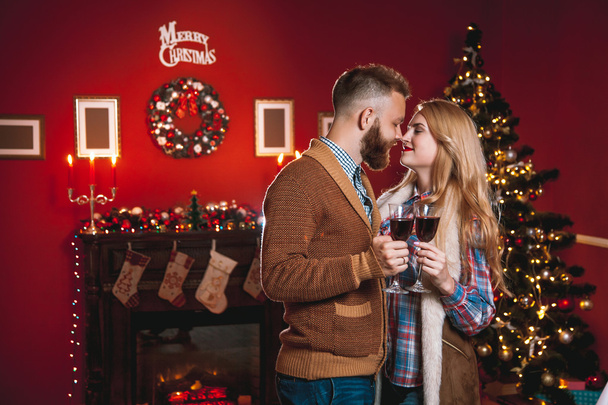 Beautiful couple in a decorated festive interior with a Christmas tree - 写真・画像
