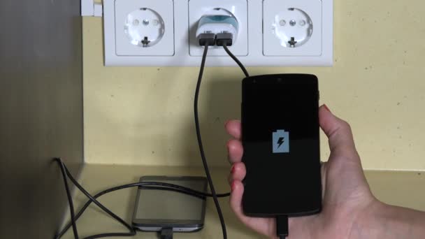 female hand holding smart phone plugged with wall charger - Πλάνα, βίντεο