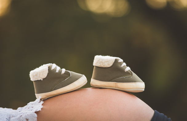Έγκυος γυναίκα με μωρό παπούτσι για το στομάχι - Φωτογραφία, εικόνα