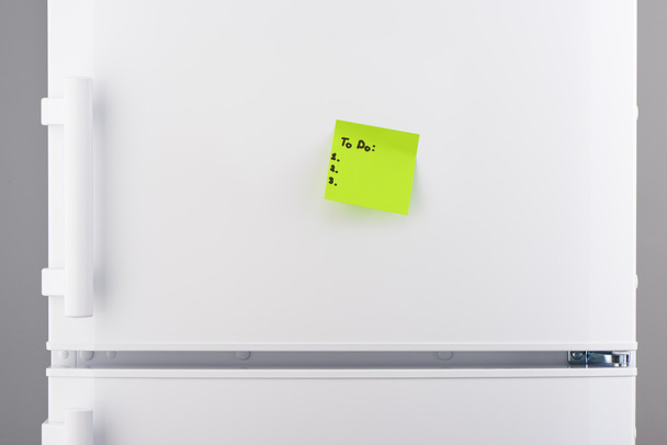 To do list on green note paper on white refrigerator  - Foto, Bild