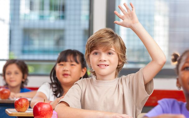 Criança escolar a levantar a mão na sala de aula. Conceito de educação
 - Foto, Imagem