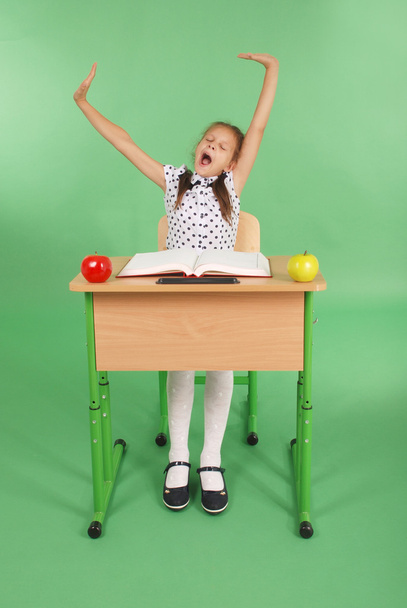 Chica con uniforme escolar sentada en un escritorio y bostezos
 - Foto, imagen