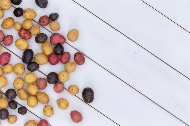 Scattered fresh multicolored baby potatoes - 写真・画像