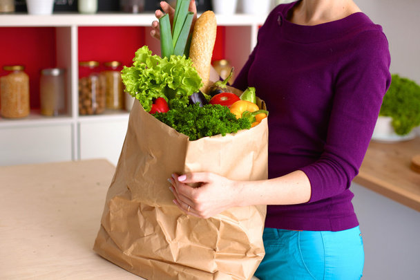 Mujer feliz positiva saludable sosteniendo una bolsa de compras de papel llena de frutas y verduras
 - Foto, Imagen