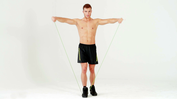 Hombre musculoso guapo haciendo ejercicio con goma sobre blanco
 - Metraje, vídeo