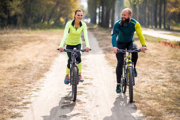 Gülümseyen çift parkta Bisiklete binme  - Fotoğraf, Görsel
