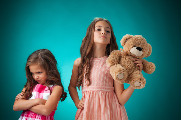 The two cute little girls on blue background with Teddy bear - Foto, Imagen