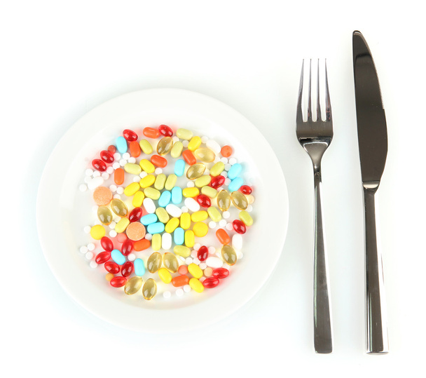 a lot of pills in a plate with knife and fork isolated on white - Fotografie, Obrázek