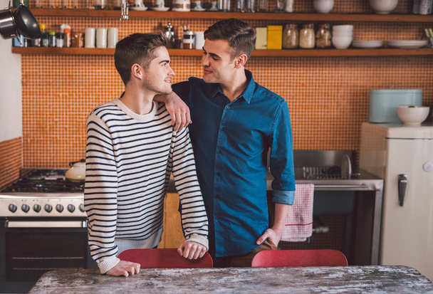 gay couple standing side by side in kitchen - 写真・画像