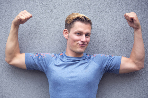 portrait of blond sportsman showing off his muscles - Photo, image