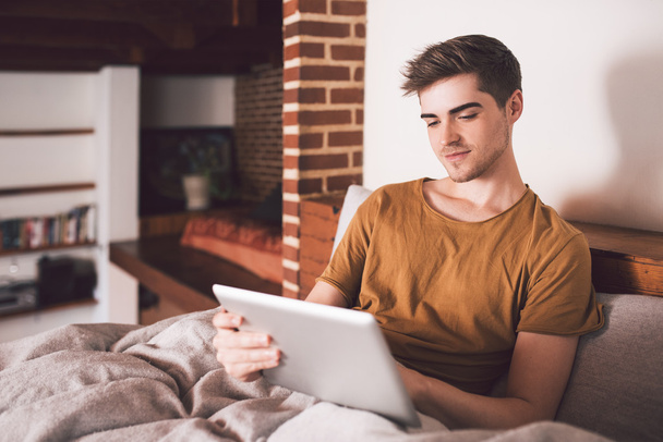 man using tablet while sitting up in bed - Foto, imagen