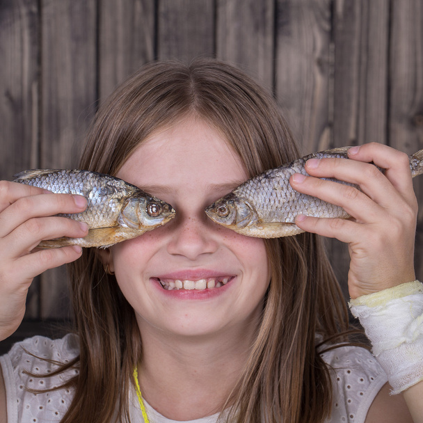 Portrait young girl together with the dried fish, close up - 写真・画像