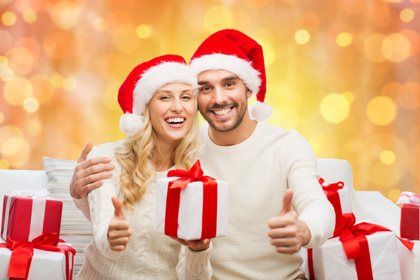 happy couple with christmas gifts and thumbs up - 写真・画像