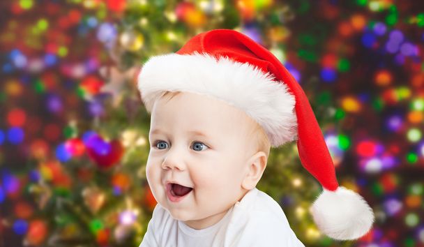 baby boy in christmas santa hat over blue lights - Foto, Imagen
