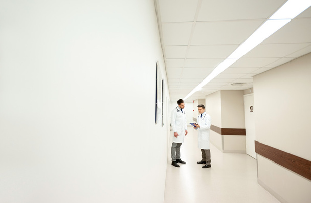 male doctors with clipboard at hospital corridor - 写真・画像