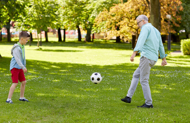 old man and boy playing football at summer park - Foto, afbeelding
