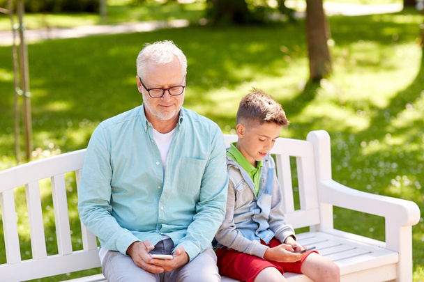 old man and boy with smartphones at summer park - Foto, Bild