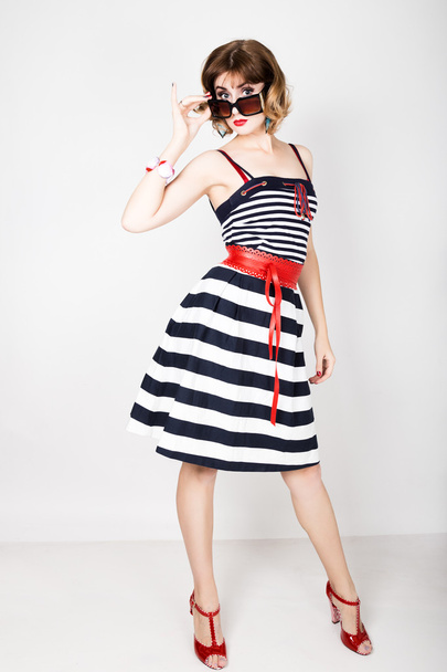 beautiful young woman in a striped dress holding over size sunglasses - Foto, Imagem
