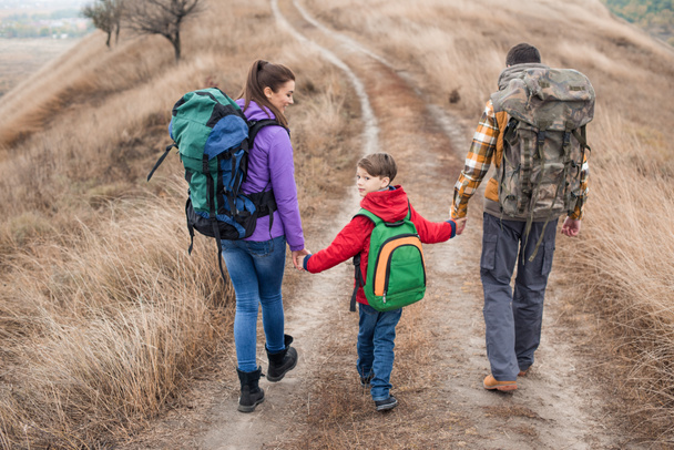 Family with backpacks walking on rural path - Photo, Image