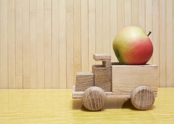 Toy wooden car with red apple - Fotoğraf, Görsel