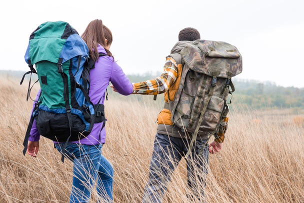 Young couple with backpacks walking in countryside - 写真・画像