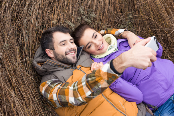 Happy couple taking selfie in grass - Photo, Image