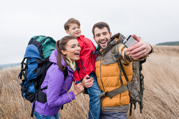 Famille heureuse avec sacs à dos prenant selfie
 - Photo, image