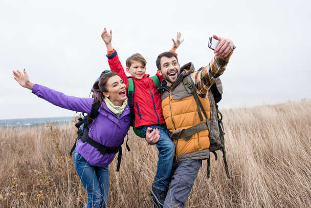 Happy family with backpacks taking selfie - Foto, Imagem