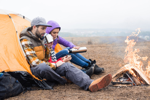 Yanan ateşi yakınındaki çay içme aile - Fotoğraf, Görsel