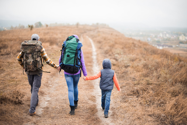  Family with backpacks walking on rural path - Photo, Image